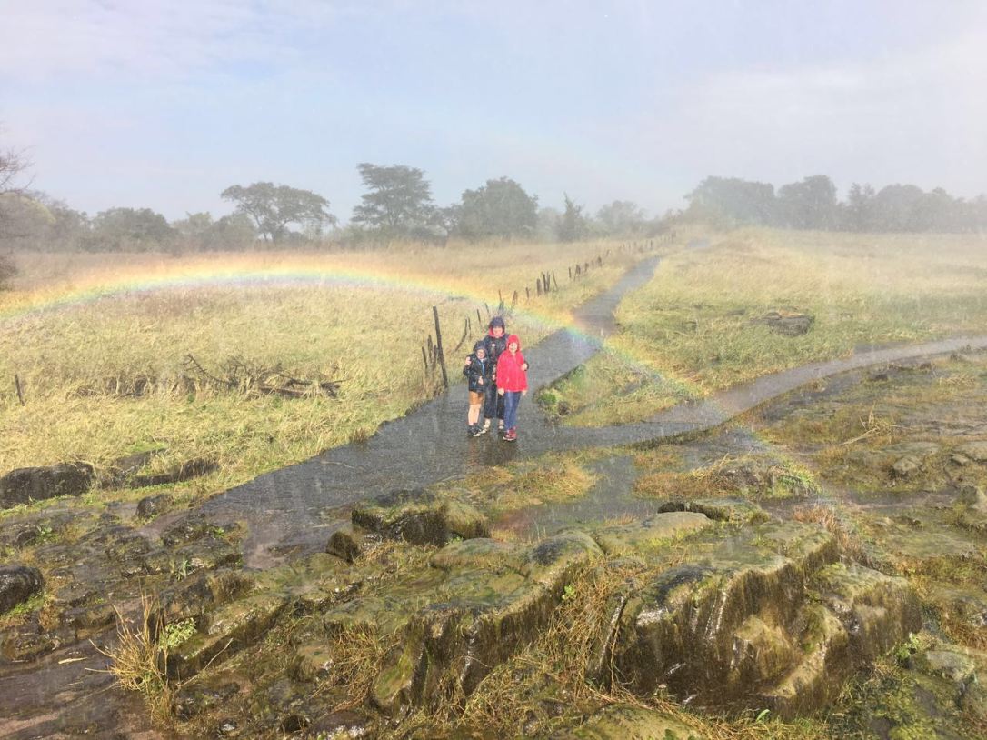 Family posing next to rainbow in Victoria Falls National park, Zimbabwe.
